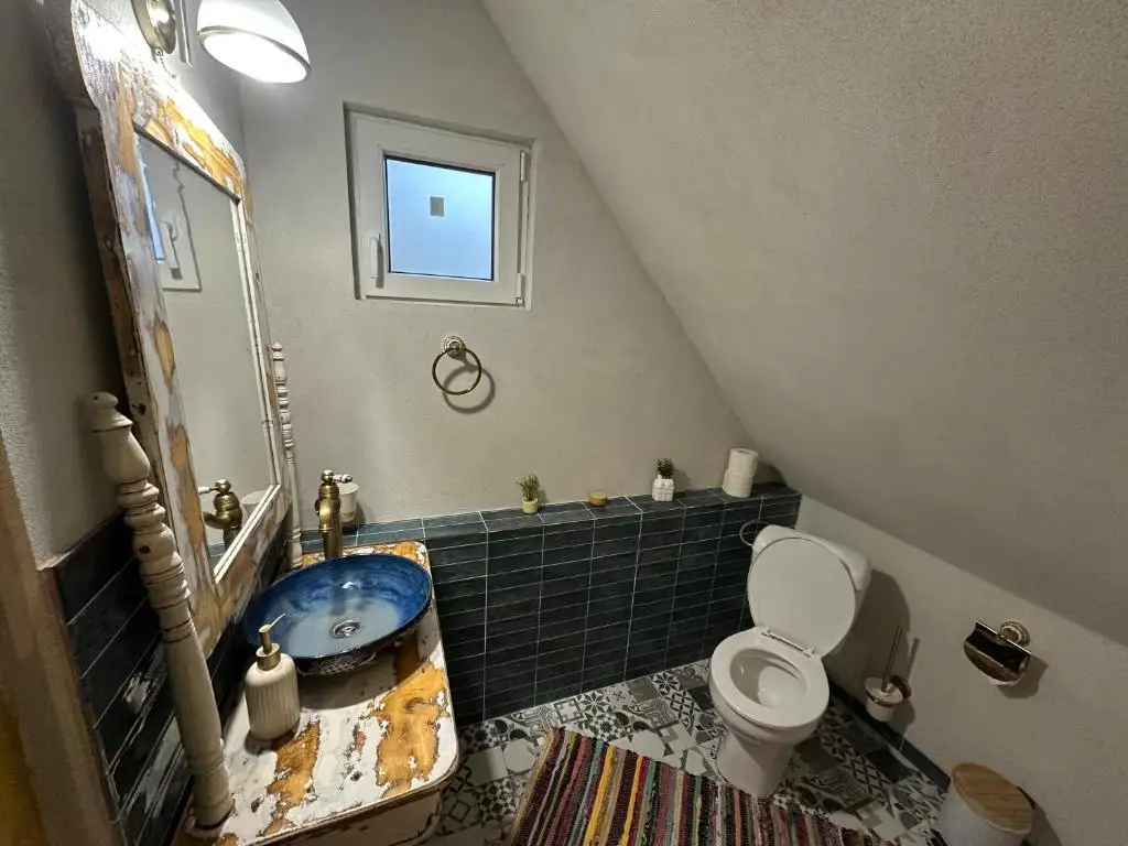 Attic bathroom with teal tiles, a blue ceramic basin set on a reclaimed-wood vanity and a distressed antique mirror