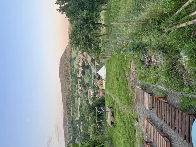 Valley view from the pool terrace with rolling green hills and the village below