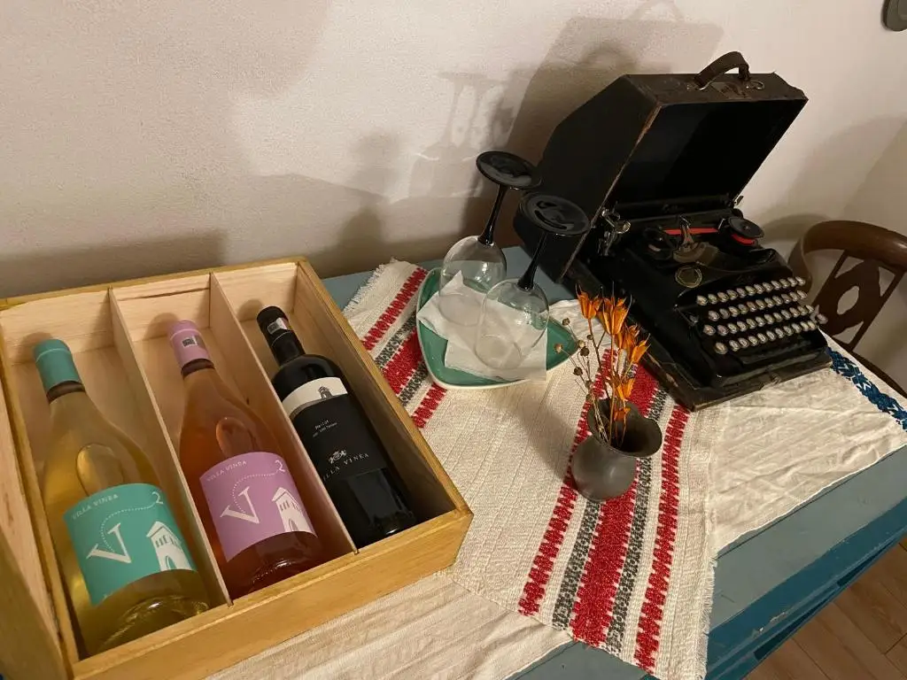 Wooden case of local Villa Vinea wine beside an antique typewriter on a hand-woven table runner