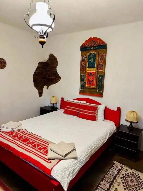 Detail of the red room: painted wall cabinet with folk motifs above the bed, woven bedspread with red lettering